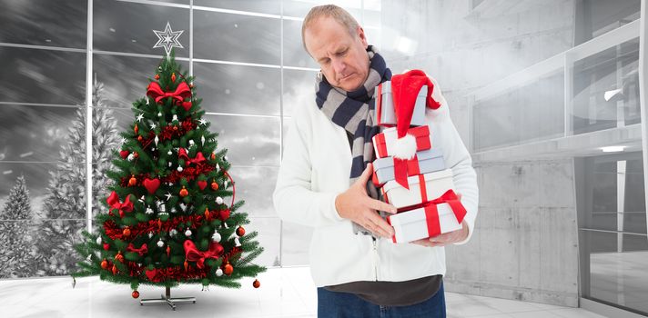 Festive man holding christmas gifts against home with christmas tree