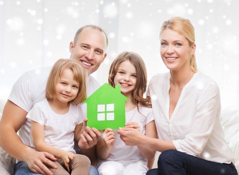 real estate, family, people and home concept - smiling parents with two little girls holding green paper house