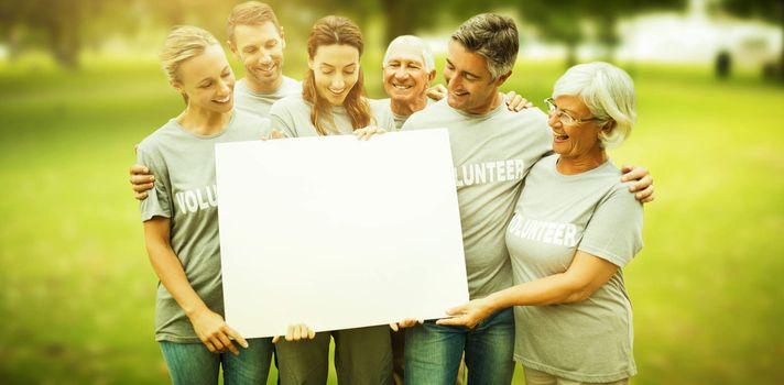 Composite image of happy volunteer family holding a blank 