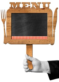 Hand of chef with white glove holding an old empty blackboard with wooden frame with text menu, wooden cutlery and checkered tablecloth