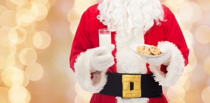 christmas, holidays, food, drink and people concept -close up of santa claus with glass of milk and cookies over beige lights background