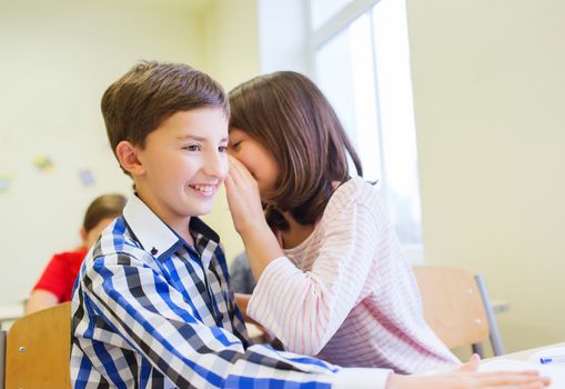 smiling schoolgirl whispering to classmate ear