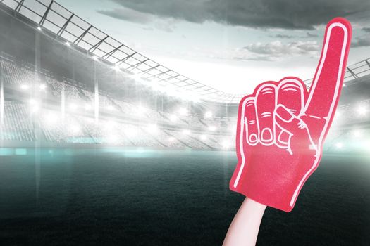 Composite image of american football player holding supporter foam hand