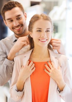 couple trying golden pendant on at jewelry store