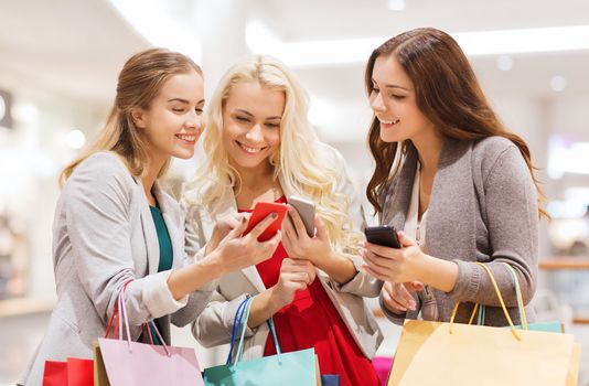 happy women with smartphones and shopping bags
