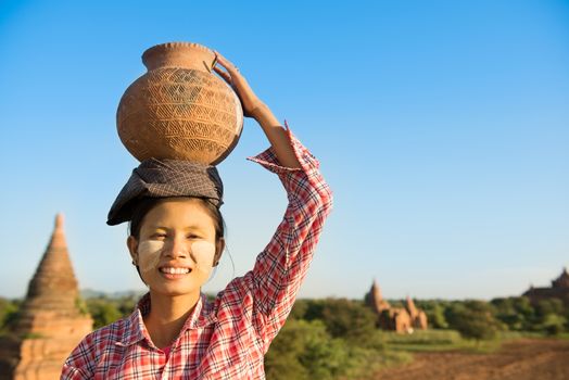 Asian traditional female farmer carrying clay pot on head