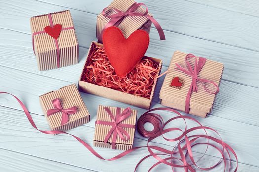 Valentines Day. Love hearts, gift boxes, presents stack. Handmade red heart, ribbons felt. Vintage retro romantic styled. Unusual creative art greeting card, wooden blue background, copyspace