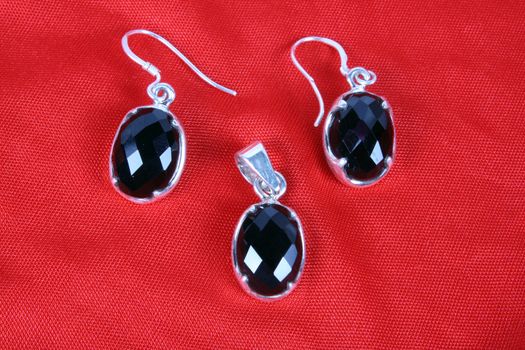 A jewelery set of a pendant and earrings made of silver and black onyx gemstones.