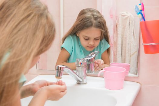 Six year old girl washes in the bathroom