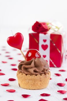 cup-cake with cherry in front of gift box 