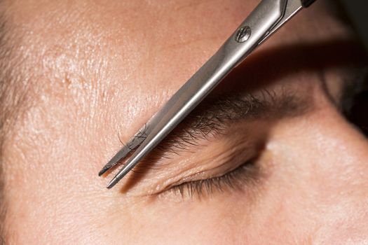Portrait of man cutting eyebrow hairs.