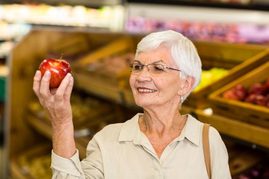 Senior woman holding and watching a red apple