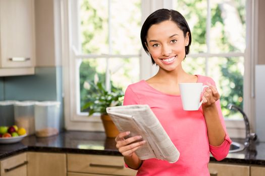 Standing brunette holding cup and newspaper
