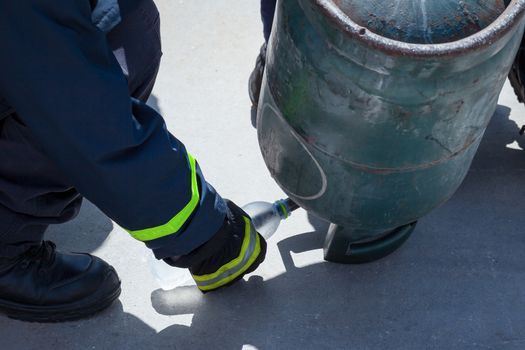 fire trainer, pouring liquid LPG gas into bottle by upside down 