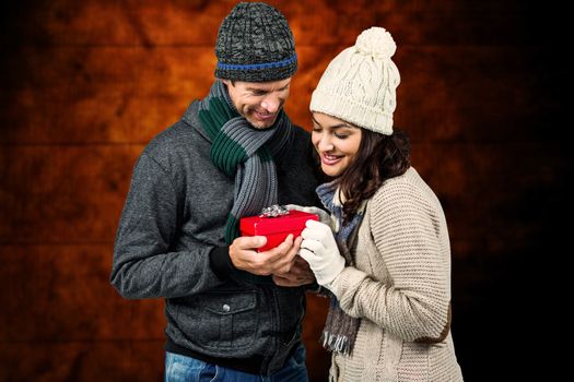 Composite image of festive couple exchanging a gift