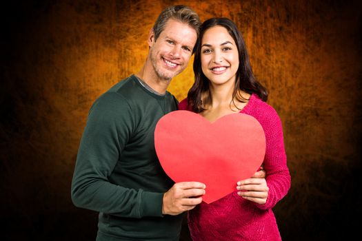 Composite image of portrait of smiling couple holding heart shape