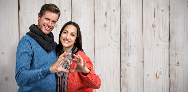 Composite image of portrait of couple making heart shape with hands