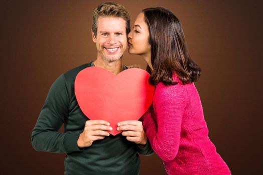 Composite image of woman kissing boyfriend with red heart shape 
