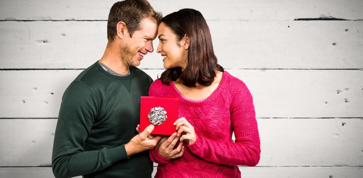 Composite image of happy couple holding gift box 
