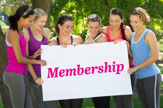 Membership against fitness group holding poster in park