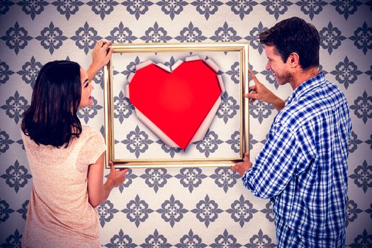 Composite image of happy couple holding picture frame