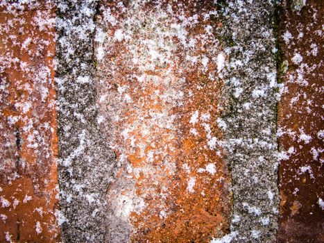 Red brick concrete wall covered with snowflakes
