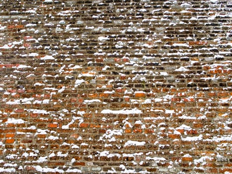 Wide red brick wall covered with snowflakes