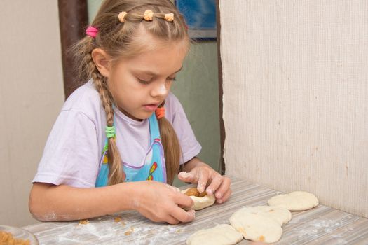Six year old girl concentrating sculpts cakes with cabbage