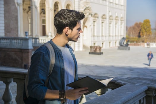 Young Man Holding a Guide Outside Historic Building