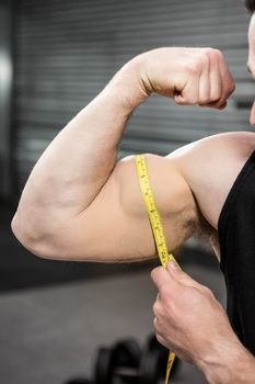 Muscular man measuring biceps