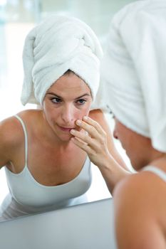 woman in a hair towel inspecting her complexion