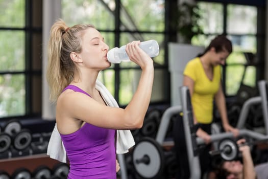 Fit woman drinking from water bottle