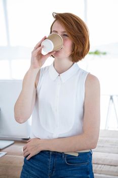 smiling hipster business woman drinking coffee in her office