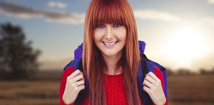 Smiling hipster woman with a travel bag taking selfie against landscape of the countryside
