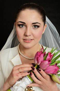 Beautiful, young bride with white veil and flowers bouquet. Female model in studio with black background.
