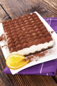 Delicious tiramisu dessert on brown wooden table. Culinary traditional sweet dessert.