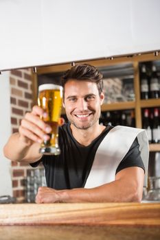Handsome barman holding a pint of beer