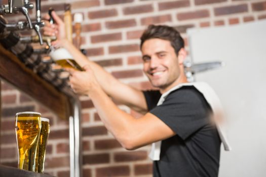 Handsome barman pouring a pint of beer
