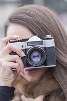 girl with a nice manicure holding vintage camera in the hands of