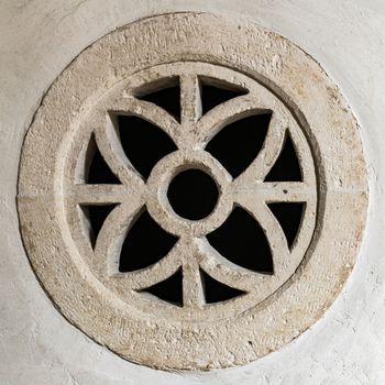 Round stone window within a symmetrical design.