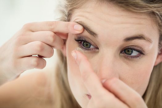Close-up of young woman applying contact lens