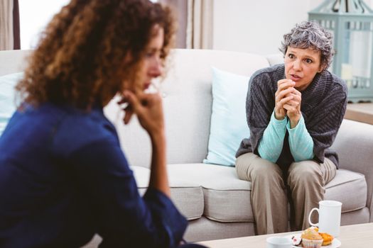 Upset mother discussing with daughter while sitting on sofa