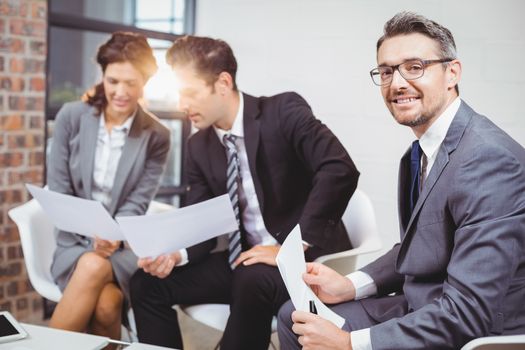 Portrait of smiling businessman with coworkers discussing
