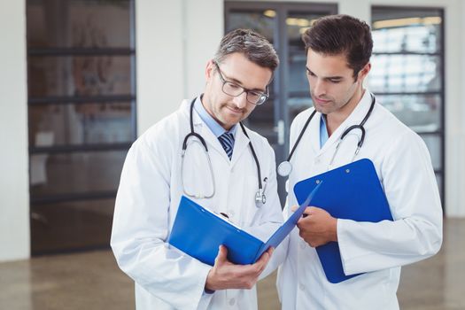 Doctors discussing while holding clipboard 
