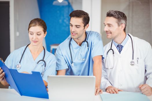 Male doctor and colleagues with clipboard while discussing