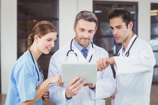 Doctors discussing while holding digital tablet 