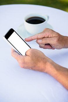 Close up of masculine hands using smartphone and having coffee