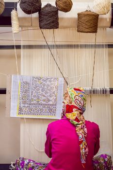 SELCUK, TURKEY – APRIL 21: Woman works at loom weaving traditional carpet on April 21, 2012 in Selcuk, Turkey.