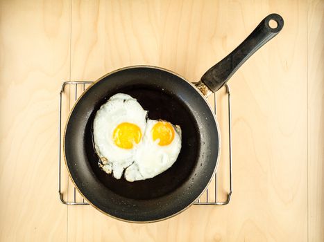 Two fried eggs on the black pan, simple top view