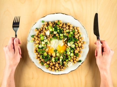 Chick peas with fried eggs, onion and hands